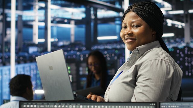 Portrait of joyous server hub technician using AI visualization insights to optimize system health. Joyful data center IT expert analyzing gear issues using node tree tools, camera B - Powered by Adobe