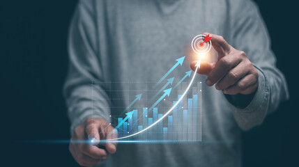 Business growth concept. Businessman hand pointing rising charts and upward arrows toward a glowing target. Symbolizing strategic planning, performance improvement and successful goal achievement.