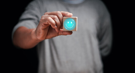 Customer satisfaction concept. Man hand holding a wooden block with glowing smiley face. symbolizing positive feedback, service quality, user experience and emotional connection in modern business.