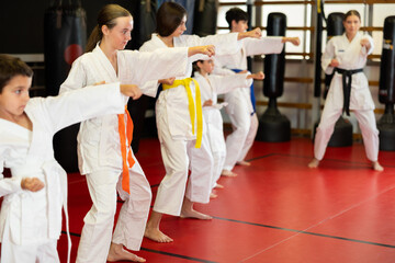 Group of teenage children of different ages for training. Boys and girls in kimono do karate in the hall. © JackF