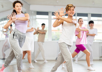 Naklejka premium Teenage boys and girl rehearse hip hop dance performance together with female instructor. Preparing for performance of choreographic team, practicing skills, repeating exercises