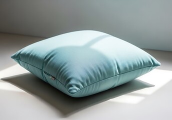 Soft turquoise pillow casting shadows on a white surface minimalism