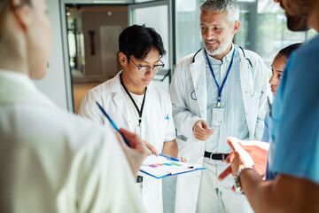 Adult and mature doctors in focused team huddle at hospital