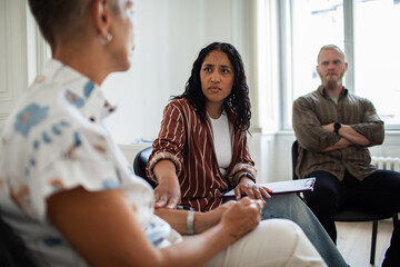 Adult support group in therapy room having serious discussion