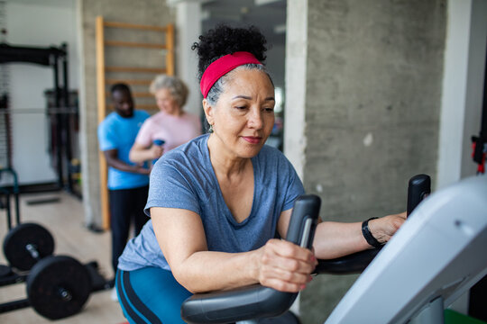 Mature woman focused while cycling on exercise bike in gym