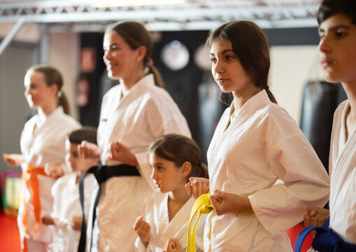 Teenage boys and girls do exercises in a white kimono, they practice karate. Children's karate section