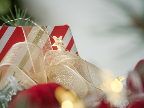 Background for personalized Christmas card. Holiday closeup red burgundy maroon velvet ornaments and gift present, evergreen spruce pine greenery branches, festive twinkle fairy lights.  - Powered by Adobe