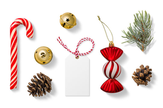 Collection of Christmas-themed elements on a transparent background, featuring a red and white candy cane, gold jingle bells, spruce branches, pine cones, a blank gift tag and festive candy ornament. 