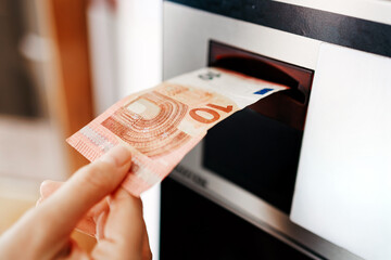 Hand of a person withdrawing cash from an ATM, showcasing a 70 euro banknote emerging from the machine, highlighting the convenience of modern banking services