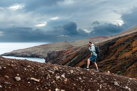 Adventurous man hiking along rocky terrain with dramatic cliffs and ocean view, showcasing the thrill of exploration in a breathtaking natural landscape
