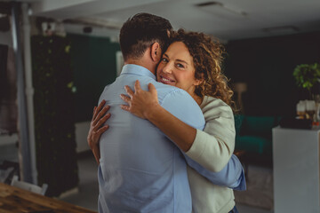 Happy adult couple embracing at home feeling love and affection