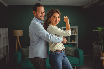 Happy couple dancing in living room at home