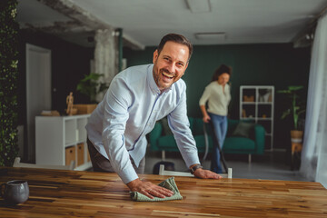 Happy couple cleaning home together sharing household chores