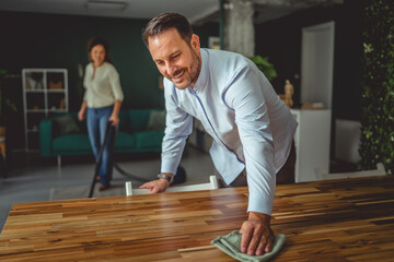 Happy couple cleaning home together sharing household chores