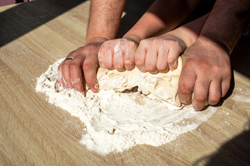 Hands of parents and children kneading dough together on a wooden surface, symbolizing family bonding, togetherness, and the passage of time through shared activities