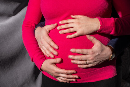 Expecting parents gently cradle a pregnant belly, showcasing love and anticipation for their upcoming child, symbolizing hopefulness and the miracle of life