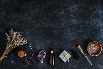Rustic arrangement of lavender, crystals and natural spa accessories on dark textured background. Top view, flat lay, copy space