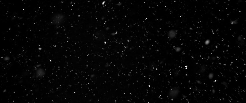 Falling snowflakes out of focus on black background for overlay blending mode. Snowing, snowfall, snow on black, selective focus