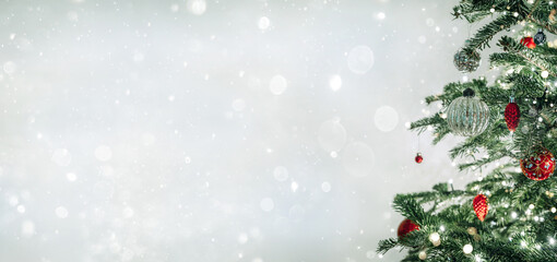 Christmas tree with red decorations on light background with bokeh, sparking, glowing. Merry Christmas and Happy New Year greeting card. Xmas and Winter holidays. Christmas wide banner
