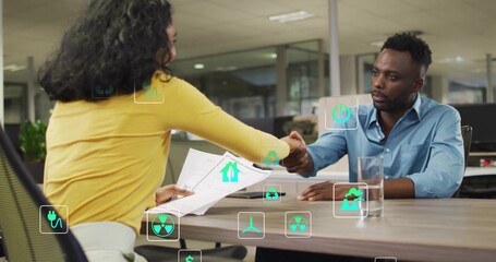 Shaking hands, woman in yellow and man in blue reviewing documents at office with energy icons
