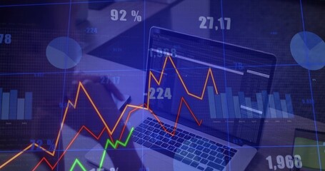 Analyzing analyst in dark blouse reviewing laptop at office desk, with charts phone overlays