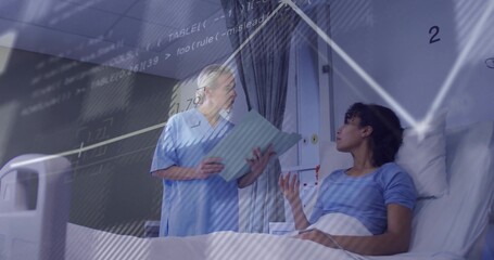 Explaining nurse in scrubs holding blue chart, consulting patient in blue gown on bed near monitor