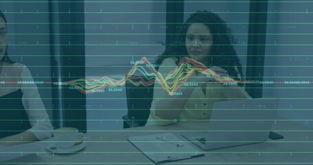 Gesturing centered woman in pale yellow blouse using virtual charts at table, laptop notebook cup