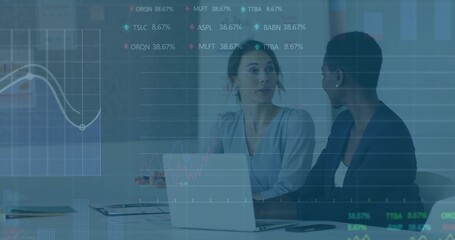 Talking two women in business clothes reviewing data charts at meeting table, with laptop