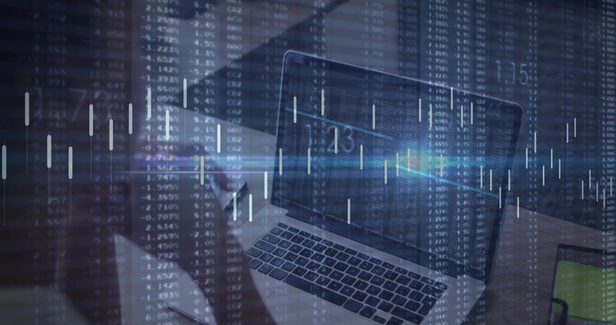 Showing laptop keys, screen at office desk, left figure wearing dark top holding phone, market data