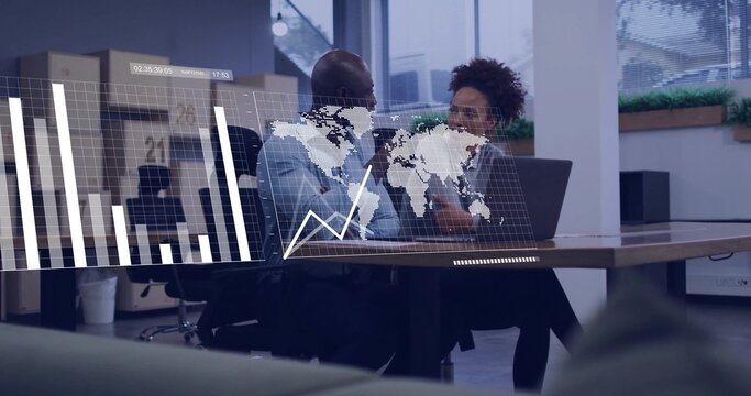 Talking coworkers gesturing at office table in blue shirt, dark blazer, laptop showing data overlay - Powered by Adobe
