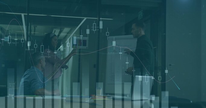 Presenting man in dark jacket pointing at flip chart in glass-walled room, laptop, market charts - Powered by Adobe