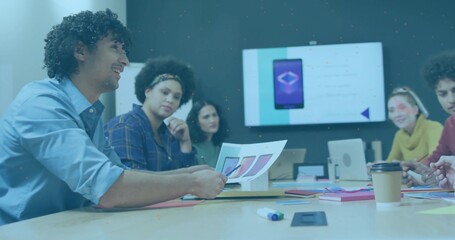 Smiling man holding printed mockups showing team at meeting room, wall display, copy space