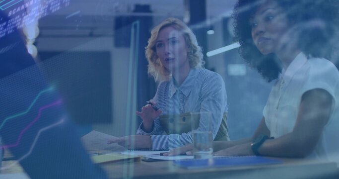 Speaking blonde woman in striped top and colleague in white blouse gesturing at table, laptop data