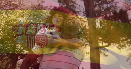 Laughing couple riding piggyback in sunlit park, woman light top, man striped polo, flag overlay