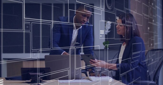 Leaning two coworkers in suits pointing at laptop and reviewing tablet at office, HUD overlays