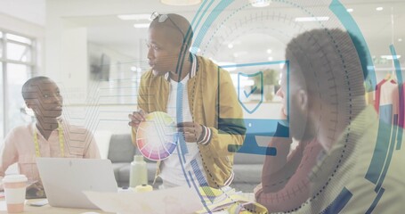 Presenting man in tan jacket holding color wheel and speaking at studio, with laptop and swatches