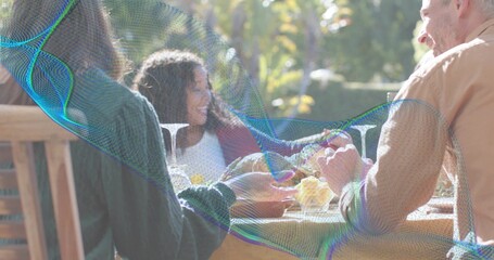 Sharing three adults reaching for bread at patio, with tablecloth, wine glasses, mesh overlay