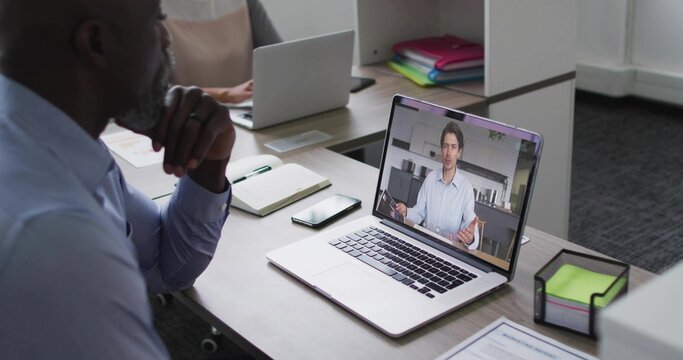 Watching man resting chin in office, wearing blue shirt, viewing presenter on laptop, copy space - Powered by Adobe
