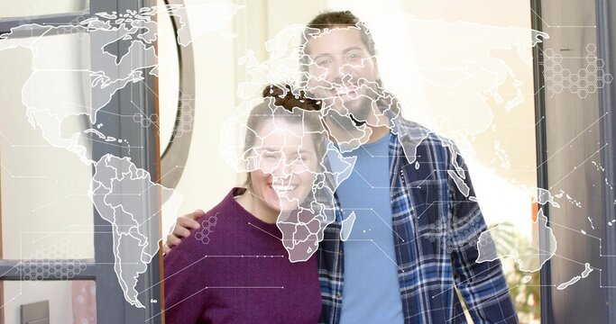 Posing couple smiling embracing at front door wearing plaid shirt and purple knit world map overlay