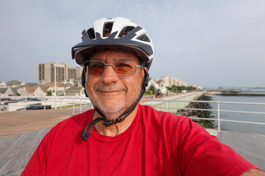 Portrait of an old Caucasian man wearing a t-shirt and a bicycle helmet smiling