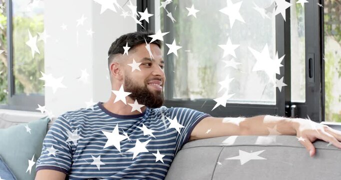 Man reacting to off-camera cue, turning and laughing on grey sofa with star overlay for marketing