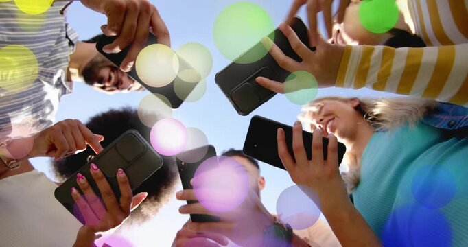 Five adults circling low cam tapping phones sharing social content causing colored circles drifting