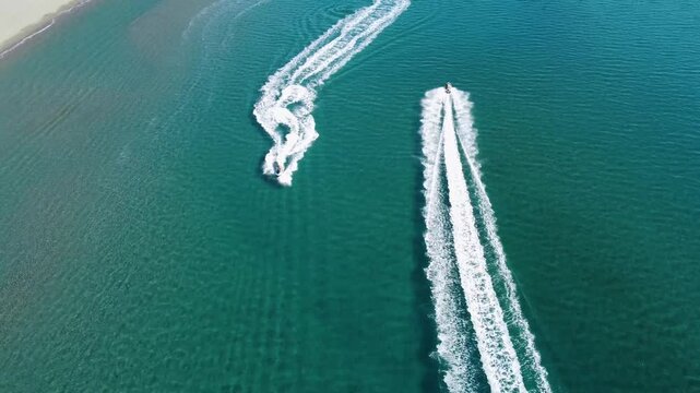Tourists rides a jet ski and makes circles on the sea. Man on personal watercraft, aerial drone view. People having fun on the sea. Jet water scooter on the sea. PWC.