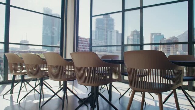 Empty boardroom with chairs and meeting table in office with large windows during daytime