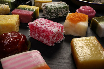 Traditional Malaysian desert Nonyah Kuih making preparing ingredients panadn leaf shredded coconut gula melaka  agar agar sagu spread over black slate messy rustic wood