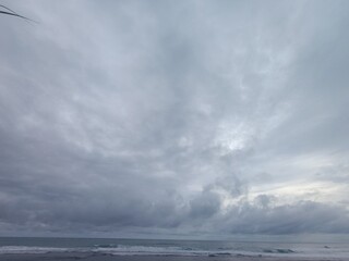 Dramatic gray and white clouds covering the entire sky over the ocean. Overcast weather pattern showing heavy atmospheric movement and mood. Wide view of a stormy sky 