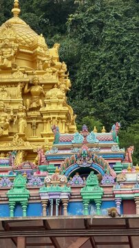 Macaque monkeys sitting on colorful Batu Caves temple