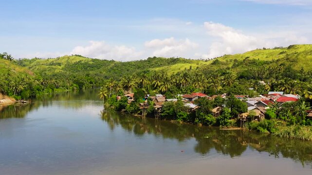 Countryside on a large tropical island. Small village on the green hills by the river. Tropical landscape in sunny weather. Village by the river. The nature of the Philippines, Samar