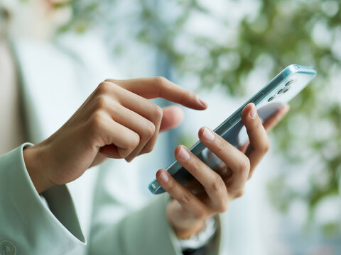 スマホを操作する女性の手元　A close-up of a woman's hands operating a smartphone　Generative AI