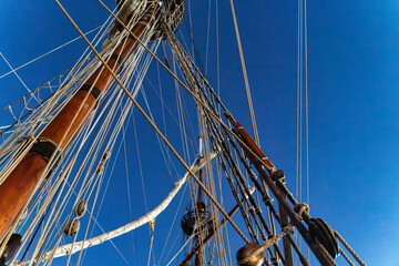 Fototapeta premium Tall Ship Mast with Furled Sails and Rigging Against Clear Sky